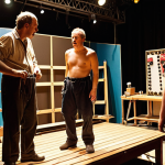 **

"A bustling backstage scene during a provincial theatre tour in France. Actors in various stages of costume adjustments, a technician repairing a prop with gaffer tape, and the director giving last-minute instructions. The set is partially visible, creating a sense of organized chaos and the energy of live theatre. Warm, slightly diffused lighting."

**